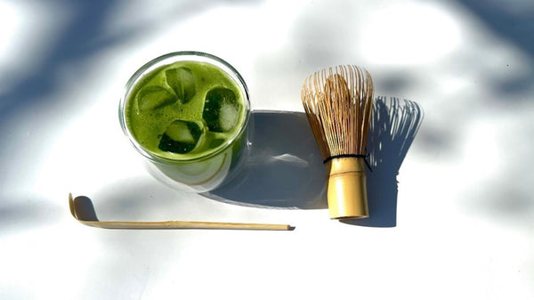 Iced Matcha on white artistic background with bamboo whisk and scoop